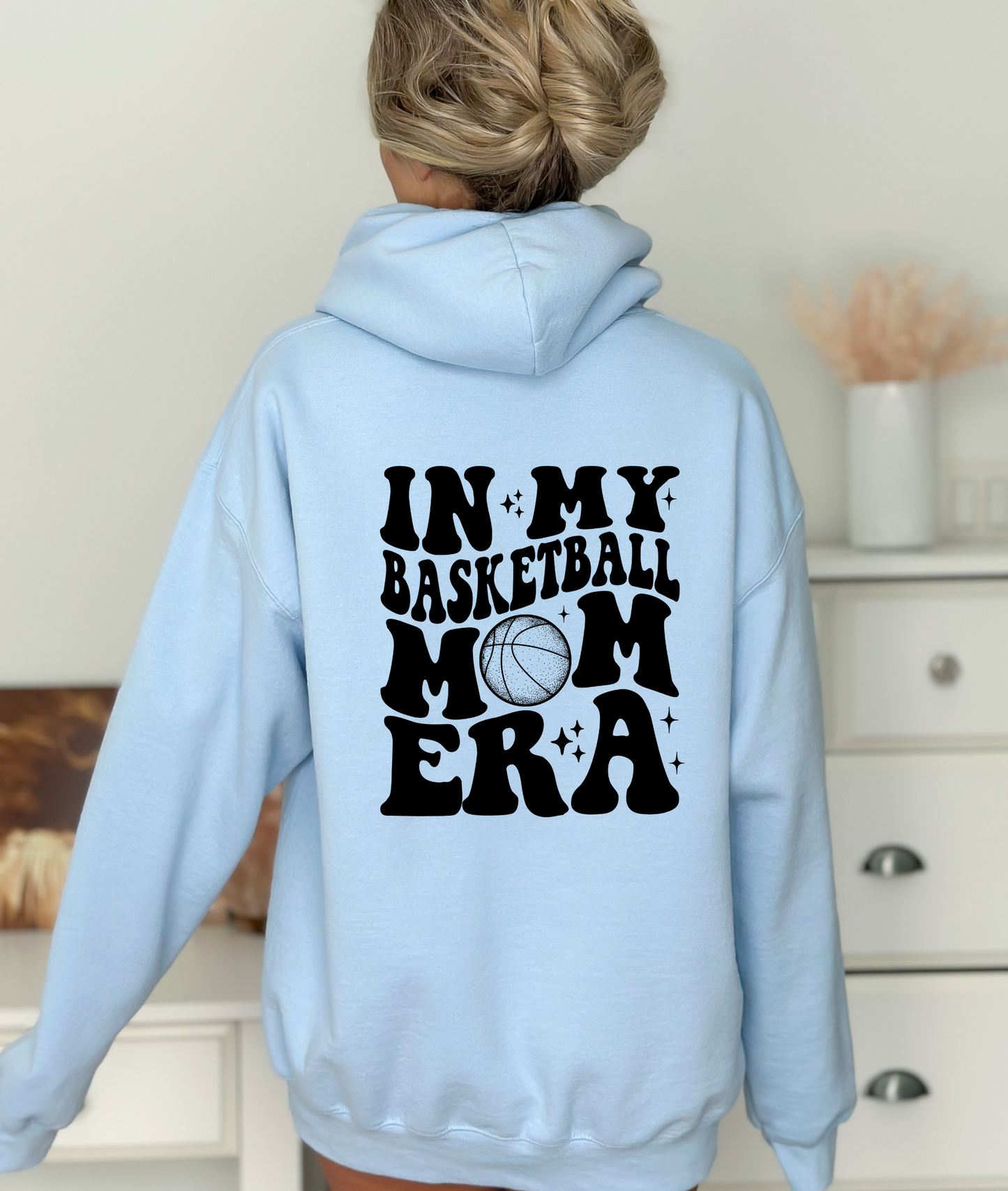 A cozy oversized hoodie for basketball mamas with the text 'In My Basketball Mom Era'. This sweatshirt is ideal for game day, offering comfort and style for basketball moms supporting their players.