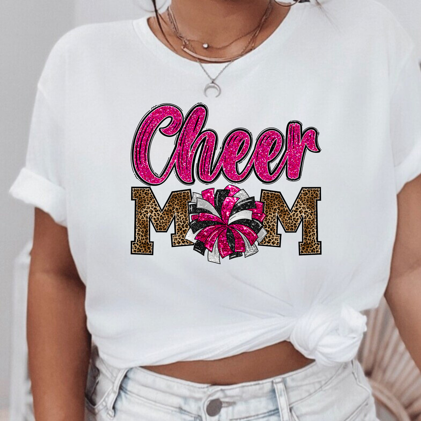 Leopard Print Cheer Mama Shirt featuring a bold design with a leopard print pattern, megaphone, pom poms, and the words 'Cheer Mama.' A stylish and trendy shirt for cheer moms to show their support. Perfect for competition cheer or everyday wear.