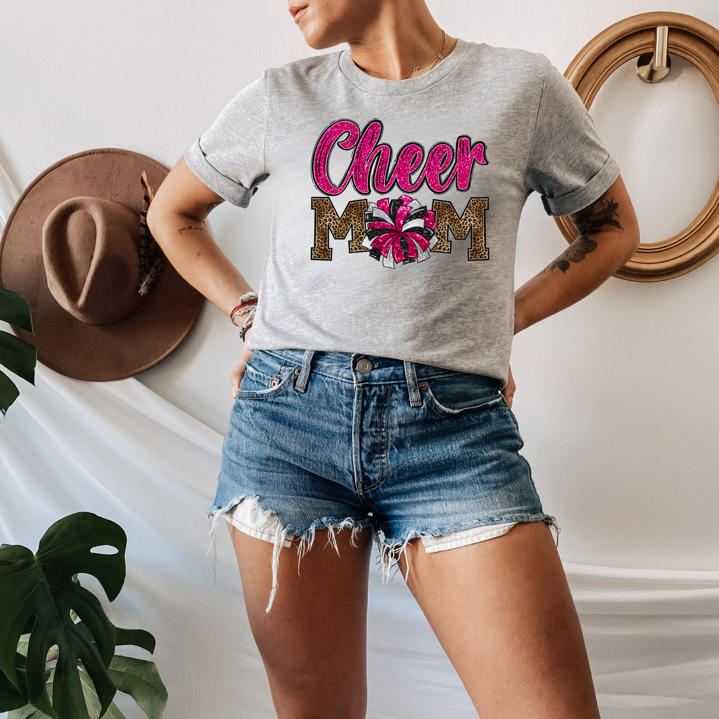 Leopard Print Cheer Mama Shirt featuring a bold design with a leopard print pattern, megaphone, pom poms, and the words 'Cheer Mama.' A stylish and trendy shirt for cheer moms to show their support. Perfect for competition cheer or everyday wear.