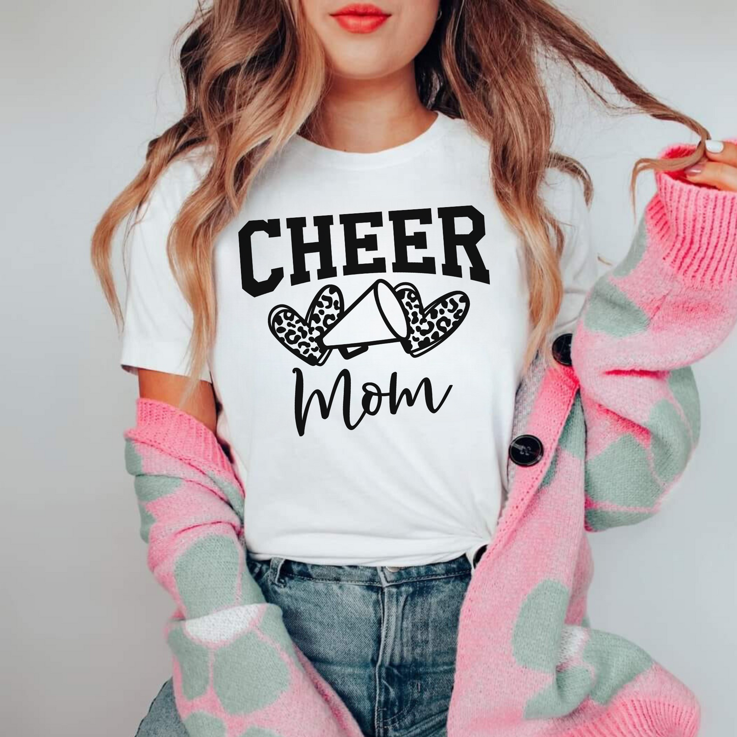 Leopard Print Cheer Mama Shirt featuring a bold design with a leopard print pattern, megaphone, pom poms, and the words 'Cheer Mama.' A stylish and trendy shirt for cheer moms to show their support. Perfect for competition cheer or everyday wear.