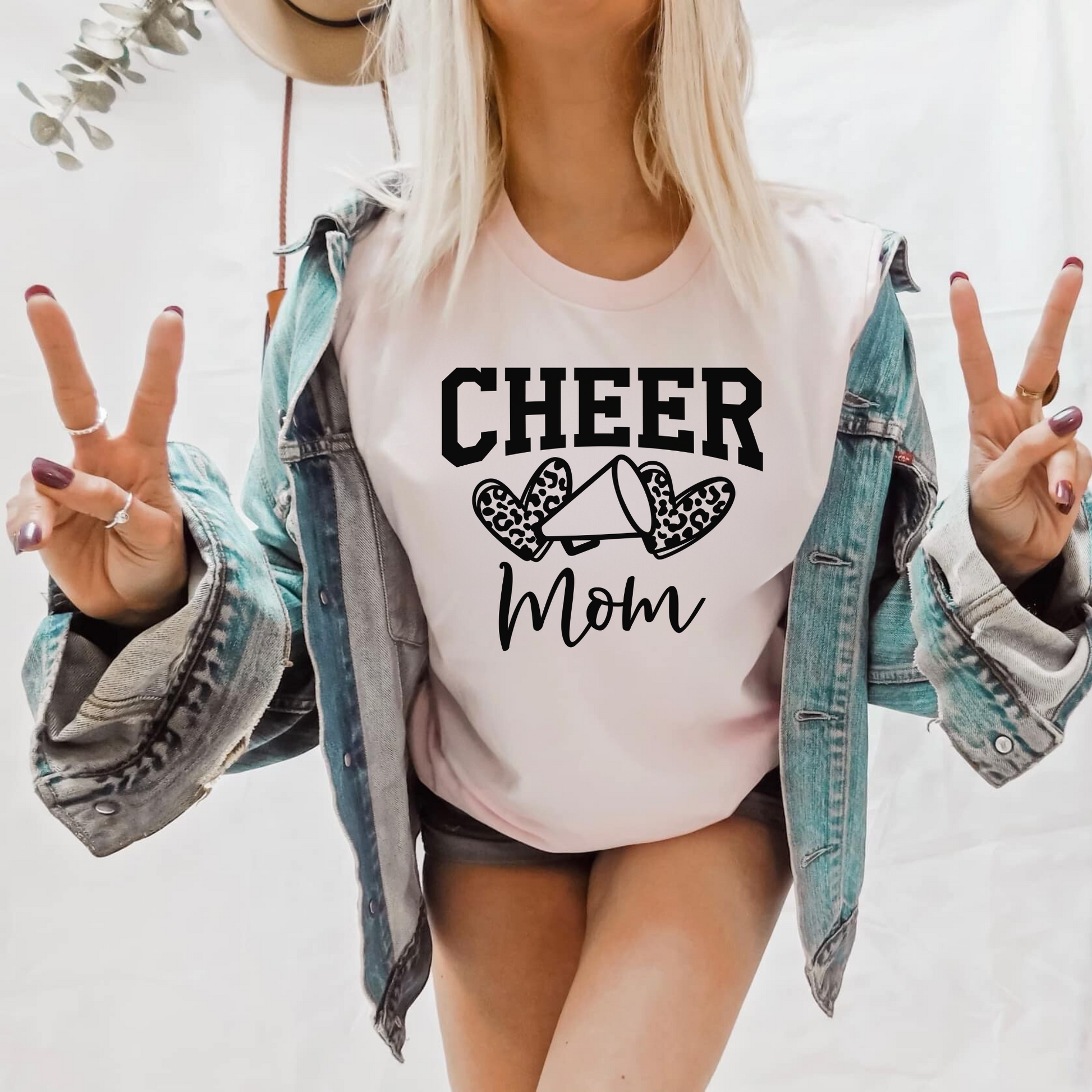 Leopard Print Cheer Mama Shirt featuring a bold design with a leopard print pattern, megaphone, pom poms, and the words 'Cheer Mama.' A stylish and trendy shirt for cheer moms to show their support. Perfect for competition cheer or everyday wear.