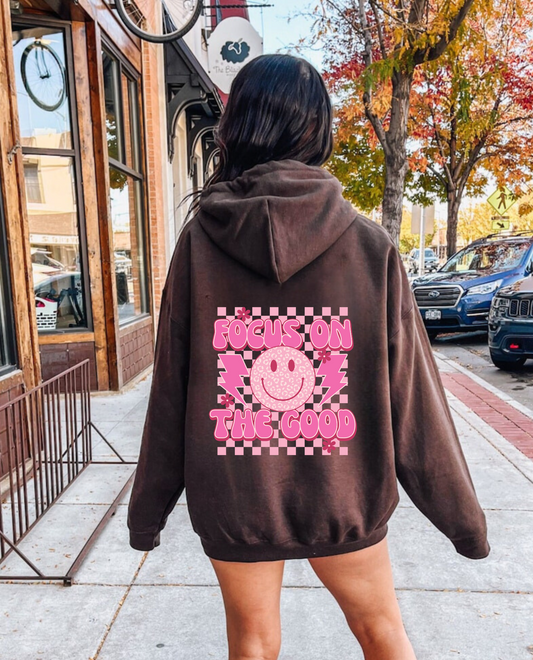 Oversized preppy hoodie with a smiley face design on the back that says 'Focus on the good'. The hoodie exudes a trendy y2k aesthetic, perfect for those seeking comfortable and stylish preppy clothing.