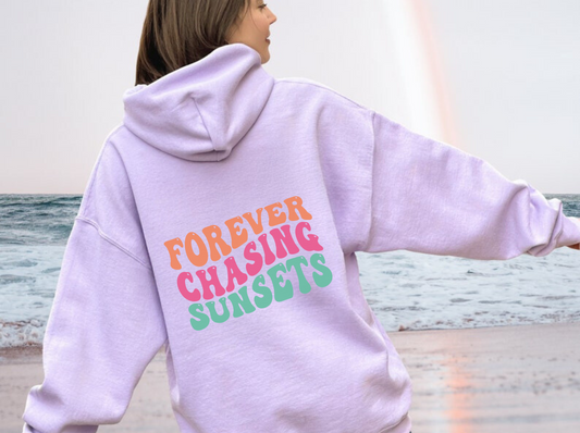 "Forever Chasing Sunsets" oversized beach hoodie sweatshirt for women, featuring a graphic print and relaxed fit. Perfect for beach outings and summer vibes.