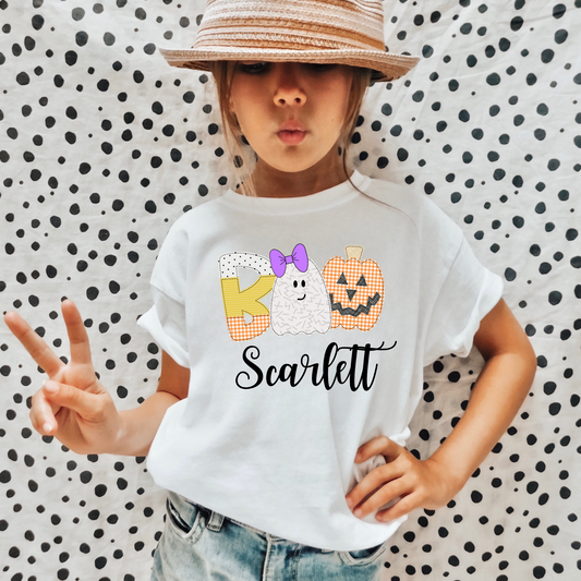 A personalized Halloween shirt for girls with a cute ghost design and her name, adding a unique and preppy touch to her Halloween outfit. The shirt embodies the spirit of Halloween with a playful 'boo' charm and pumpkin accents.