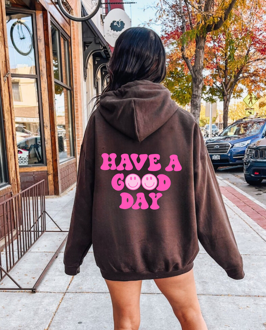 Oversized preppy hoodie with a smiley face design on the back that says 'Have a good day'. The hoodie exudes a trendy y2k aesthetic, perfect for those seeking comfortable and stylish preppy clothing.