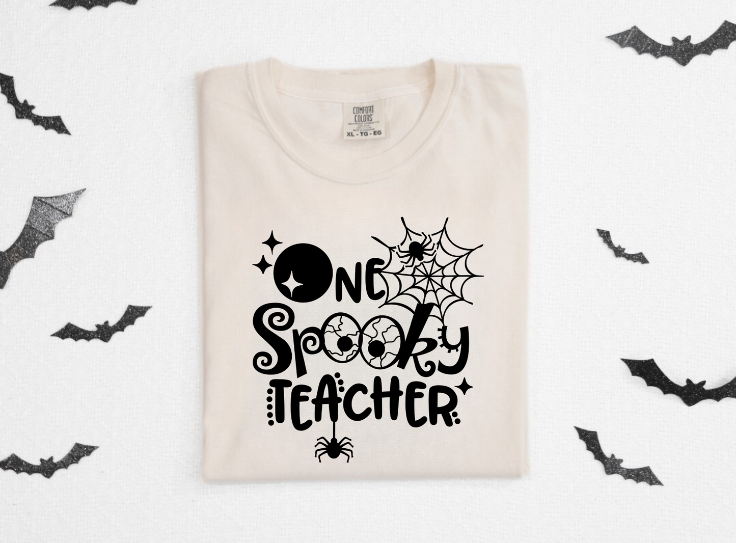 A cozy 'One Spooky Teacher' Halloween shirt, perfect for teachers looking to embrace the autumn spirit. The shirt features a playful design that adds a touch of Halloween charm to your fall outfit. Ideal for showcasing your teacher style with a dash of spooky fun.