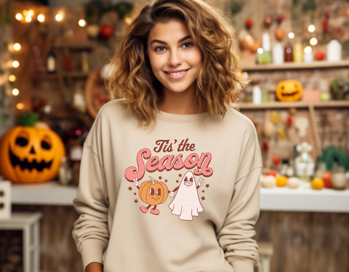 A retro, vintage Halloween sweatshirt crewneck with a cute ghost and pumpkin design. The sweatshirt features the slogan "Tis the Season" in bold, playful letters. The muted colors and vintage design add to the overall spooky aesthetic of the sweatshirt.