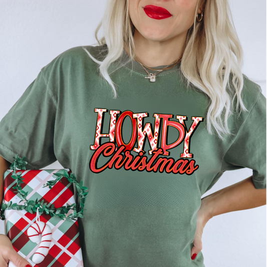 Person wearing a Comfort Colors 'Howdy Christmas' Western Christmas shirt, posing in a festive holiday setting with a fun and playful expression